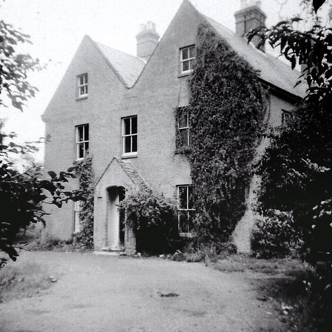 Grayscale image of an old country house covered in ivy.